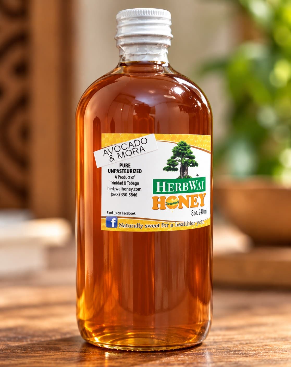 Round bottle of amber HerbWai Avocado & Mora honey, labelled Pure Unpasteurized, on a wooden table