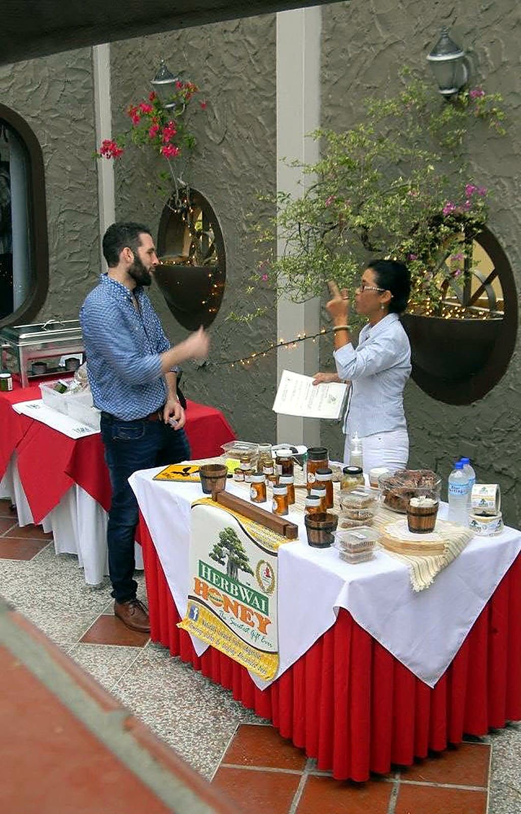 HerbWai Honey market stall with the HerbWai banner and jars of honey on a red and white table