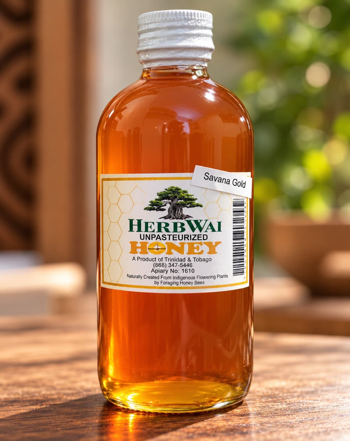 Round bottle of golden amber HerbWai Savana Gold unpasteurized honey, Apiary No. 1610 label, on a wooden table